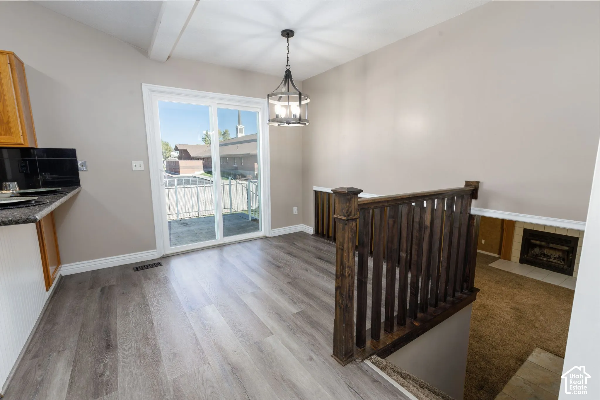 Bright upper-level room featuring gleaming wood-finish flooring, a wooden crib, pendant lighting, and glass sliding doors opening to a covered balcony with scenic vistas