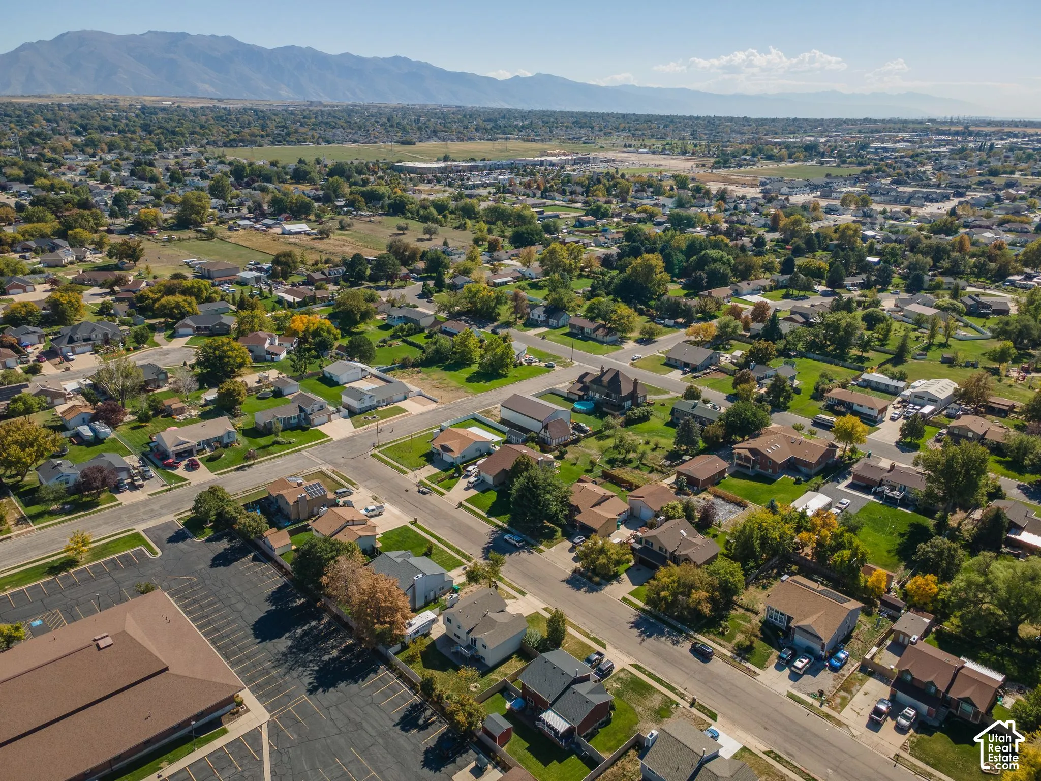 Residential neighborhood featuring single-family homes, mature trees, and mountain scenery