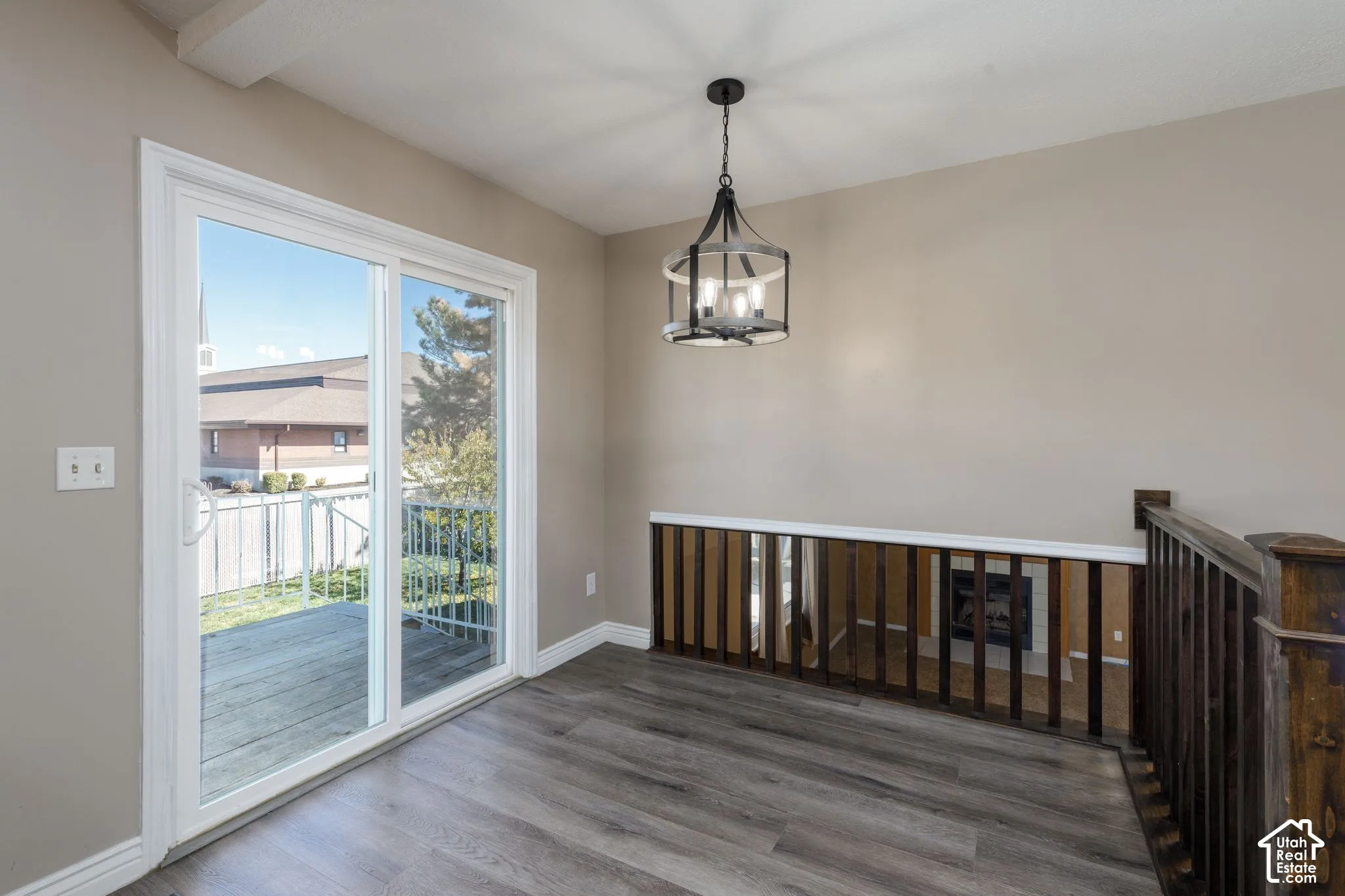 Sliding glass door access to an exterior deck, plank flooring, and an open-cage chandelier