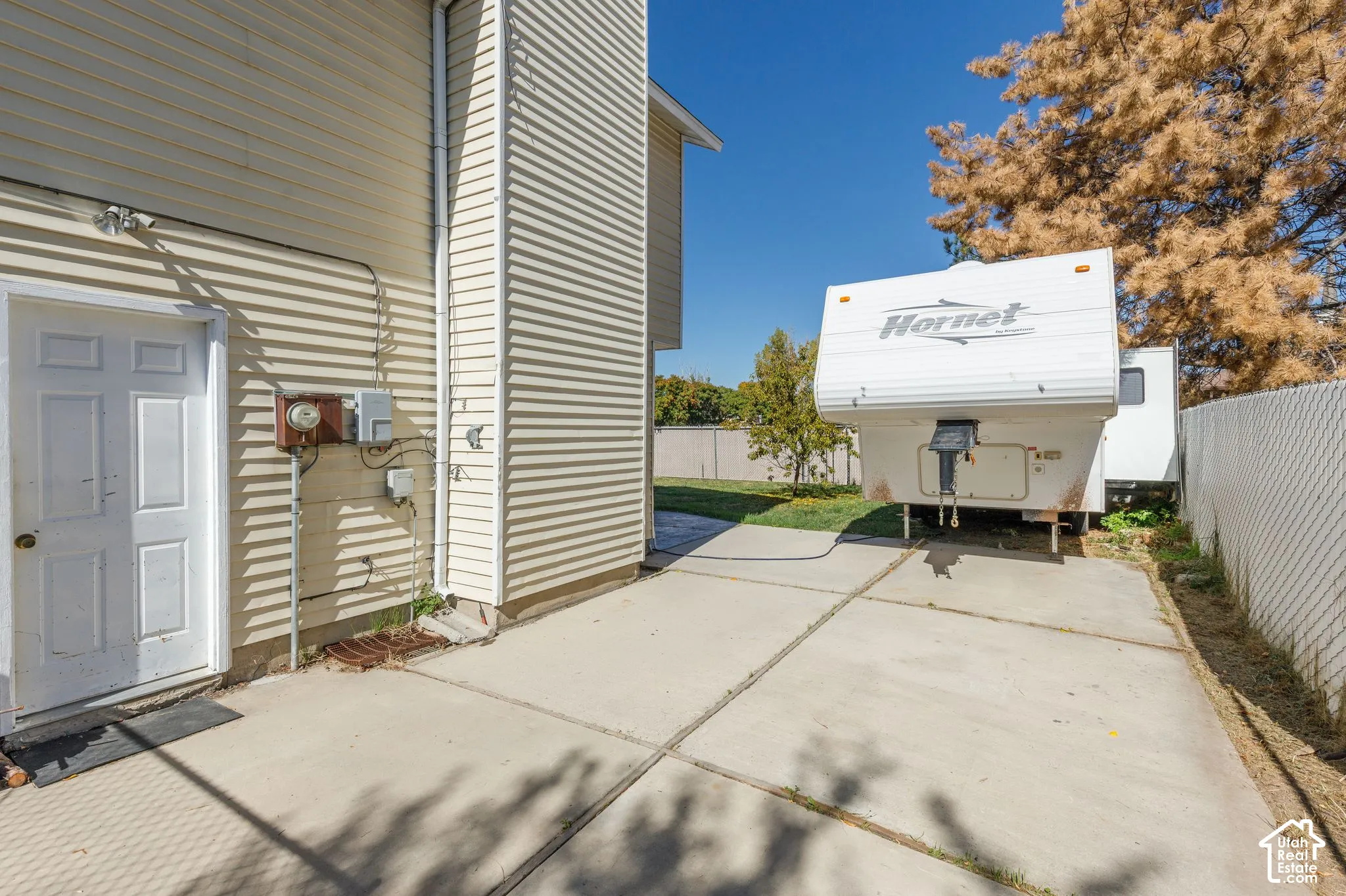 Side access door, concrete pad, horizontal siding, and chain-link fencing