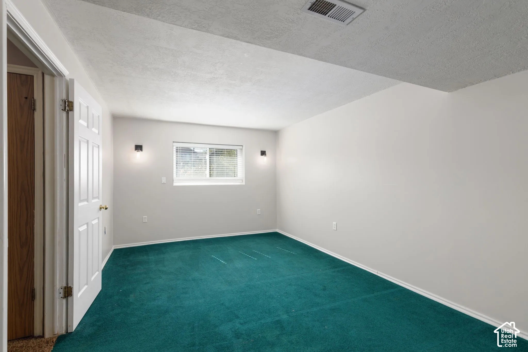 Wall-to-wall teal carpeting with white baseboards