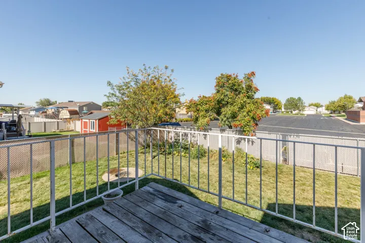 Wood-plank deck with white metal railing overlooking a fenced backyard