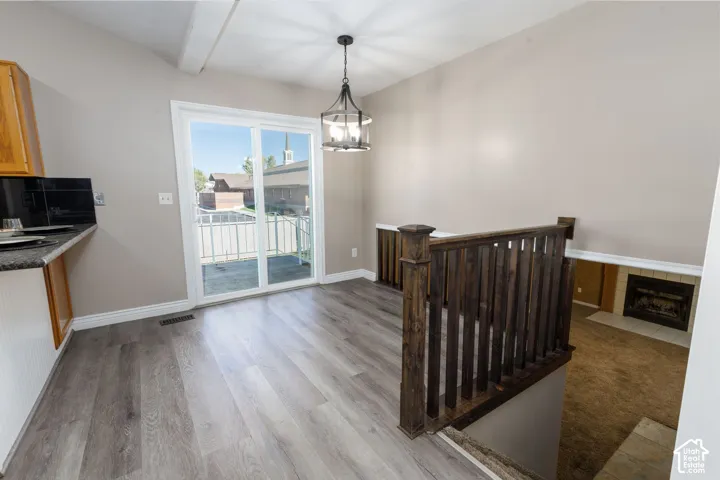Bright upper-level room featuring gleaming wood-finish flooring, a wooden crib, pendant lighting, and glass sliding doors opening to a covered balcony with scenic vistas