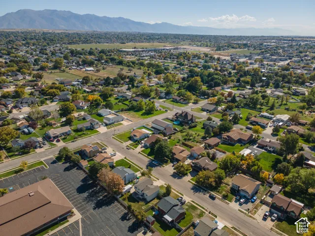 Residential neighborhood featuring single-family homes, mature trees, and mountain scenery