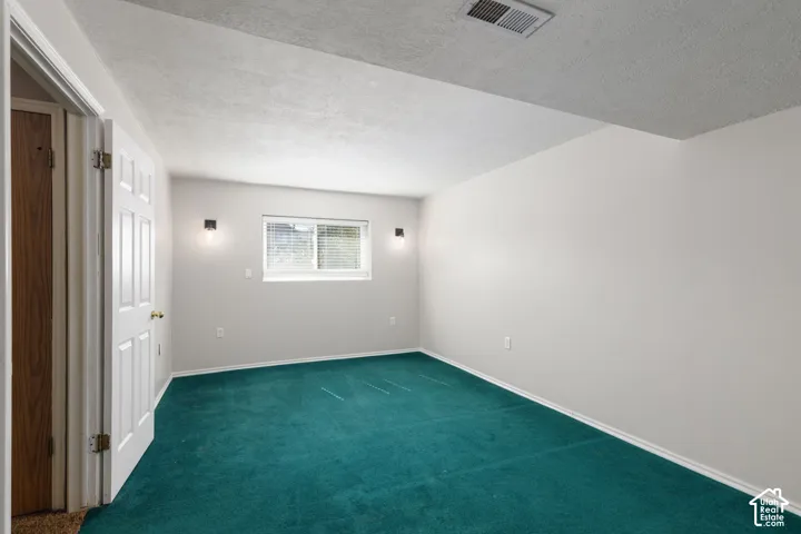 Wall-to-wall teal carpeting with white baseboards