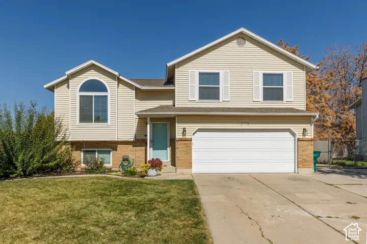Two-story residence featuring light-colored siding, brick accents, an arched window, and an attached two-car garage