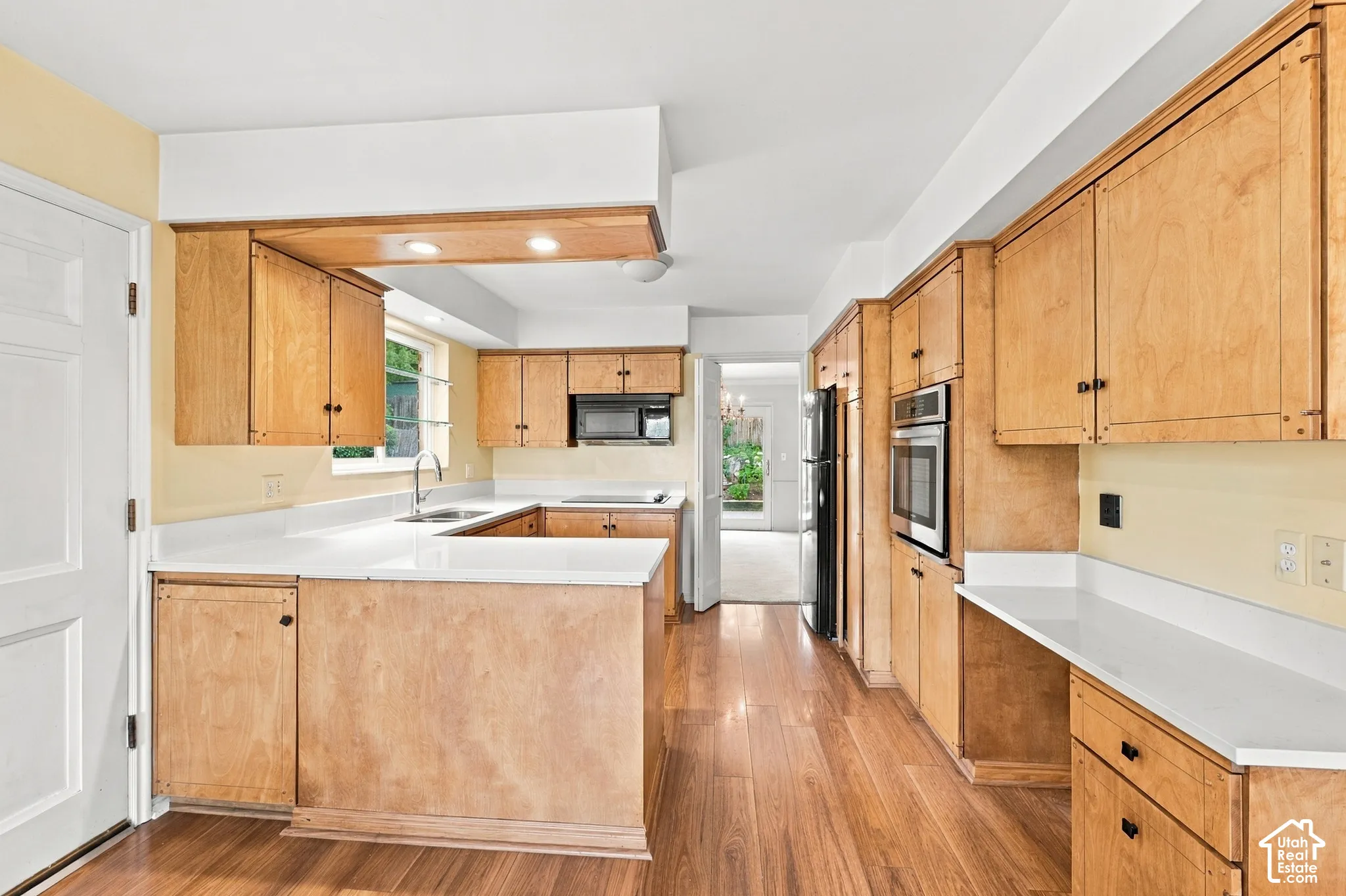 Kitchen featuring light-finish cabinetry, white countertops, built-in stainless steel oven, recessed lighting, and wood-finish flooring