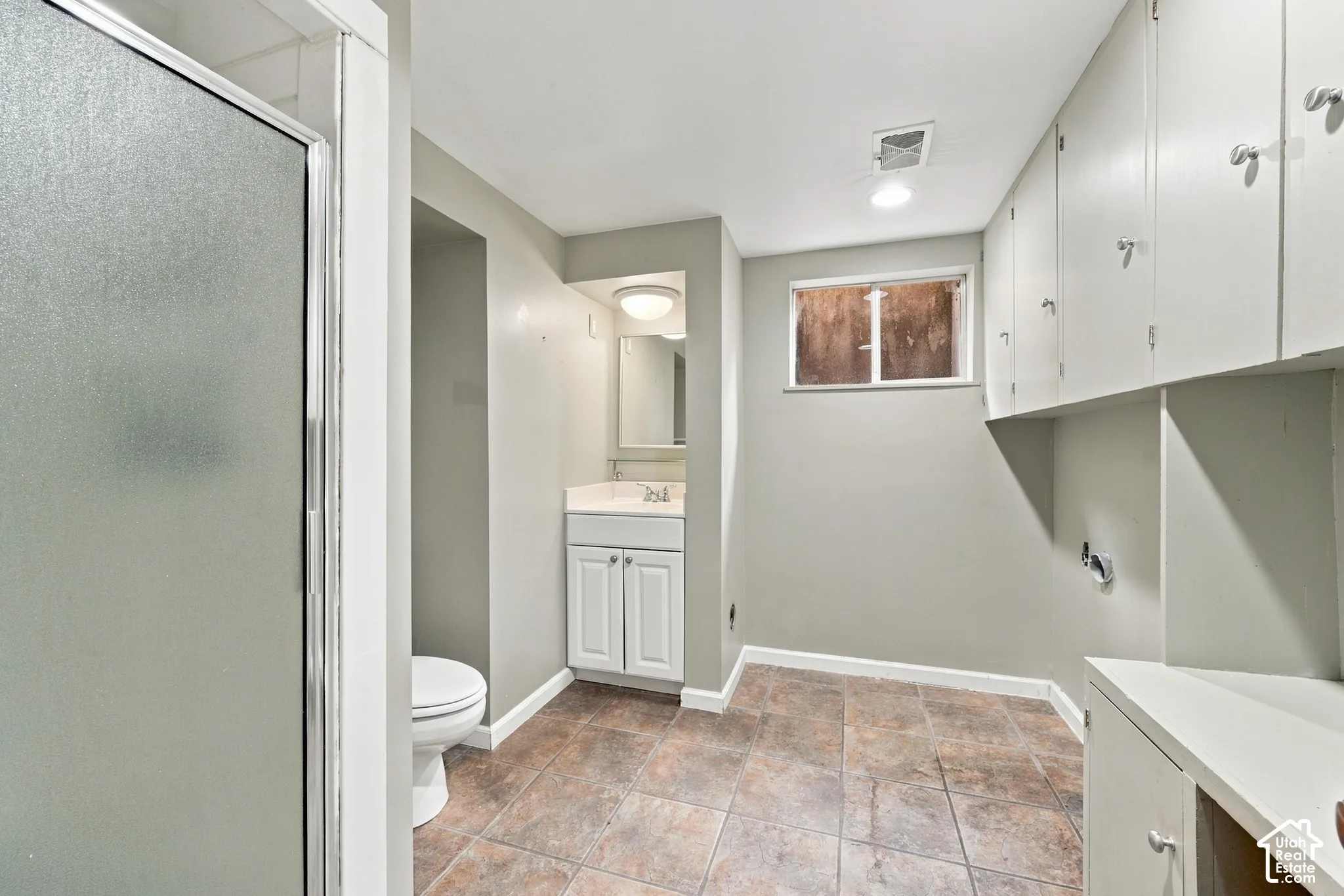 Bathroom 3 featuring a glass-enclosed shower, white vanity with integrated basin, ceramic tile flooring, and extensive built-in cabinetry