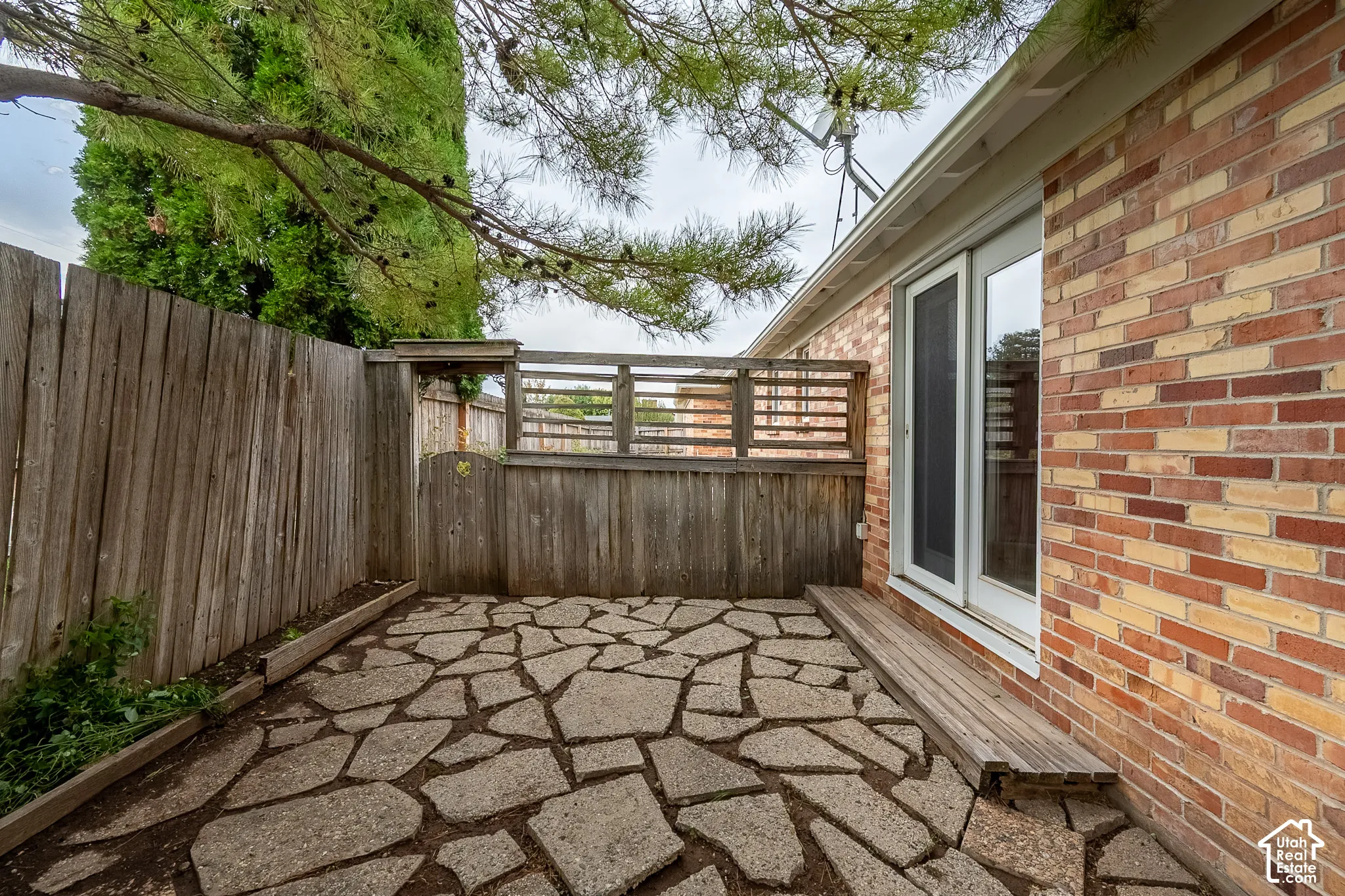 Flagstone patio featuring a wood-slat privacy fence, exterior brick masonry, and sliding glass doors
