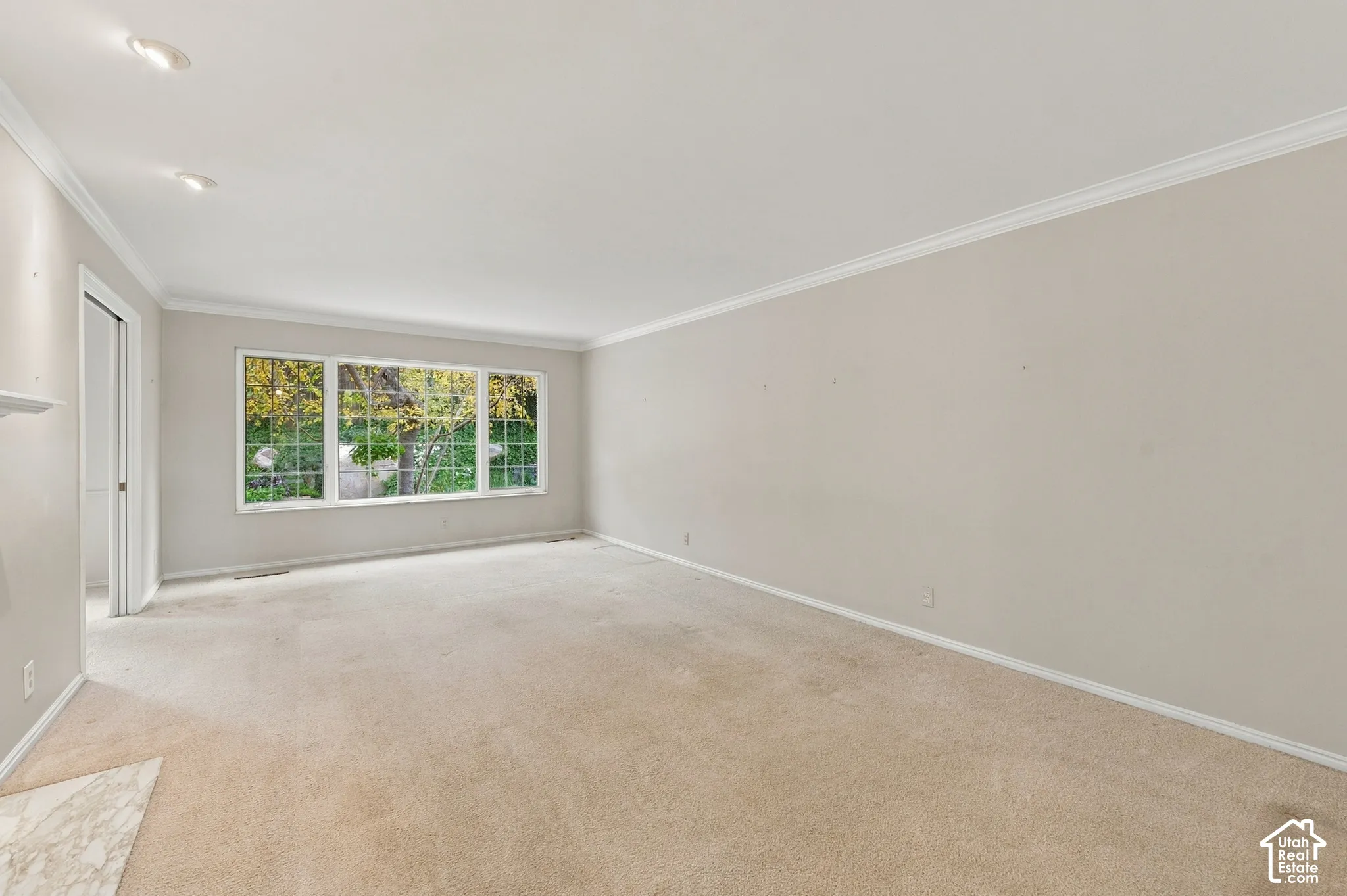 Main floor living room featuring carpeted flooring, crown molding, recessed lighting, and a large picture window