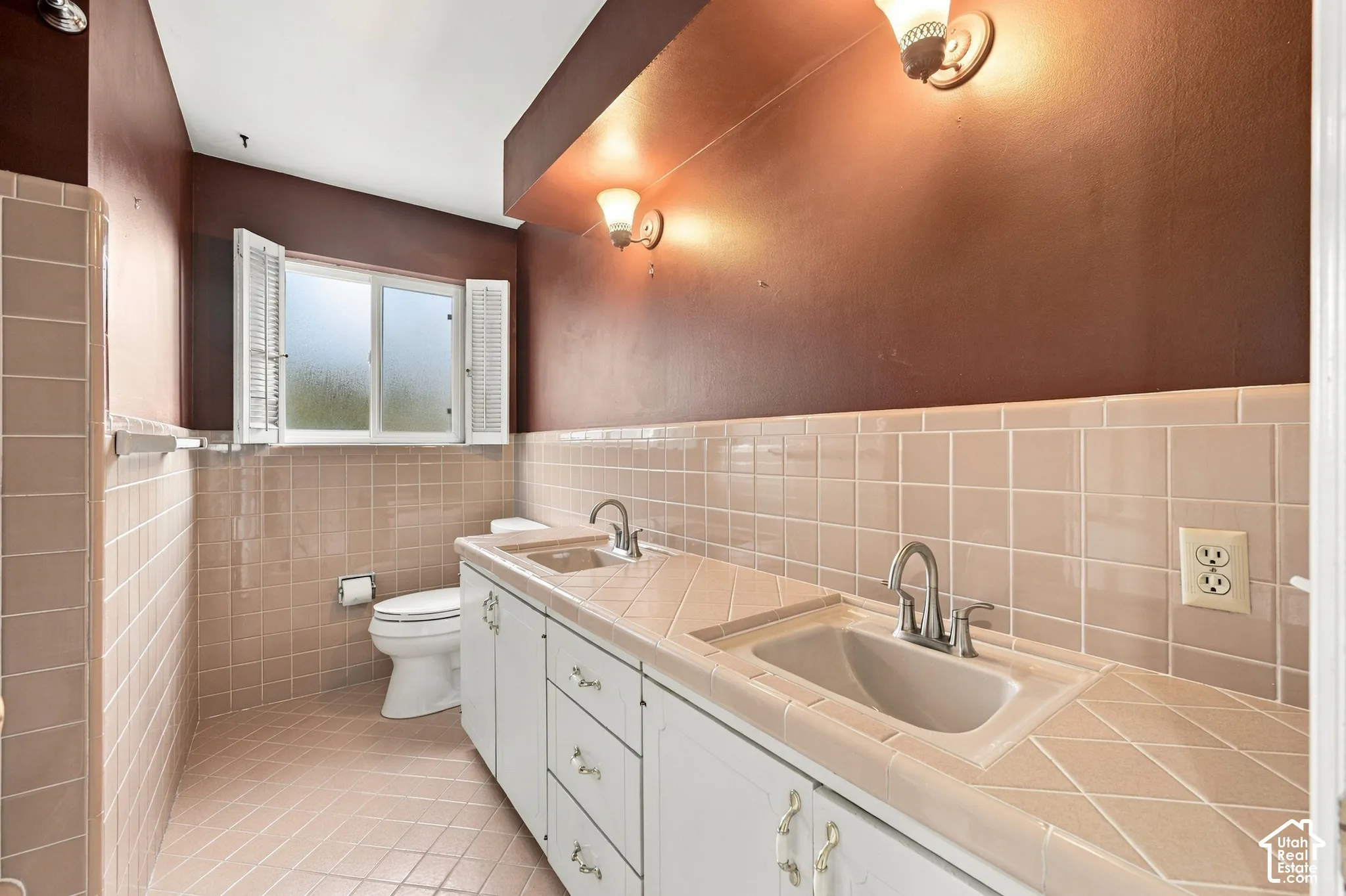 Main Bathroom featuring dual vanity with integrated sinks, tiled countertop, wall-mounted light fixtures