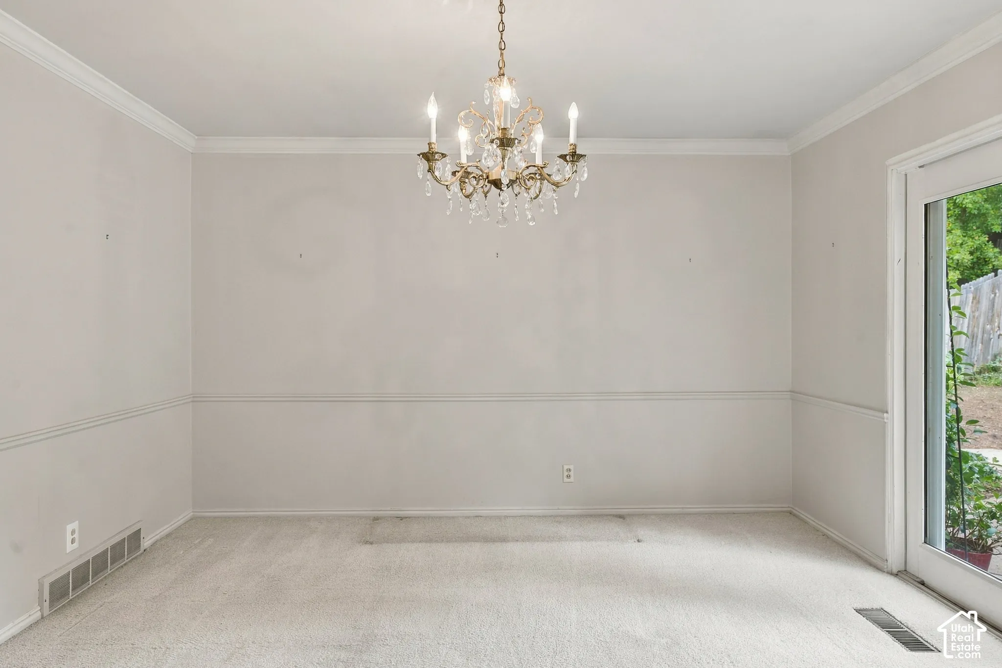 Dining Room featuring a multi-tiered crystal chandelier, crown molding, chair rail trim, and a glass-paneled exterior door