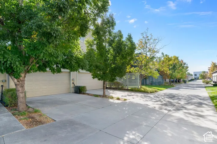 Exterior featuring a two-car garage, concrete driveway, and mature landscaping