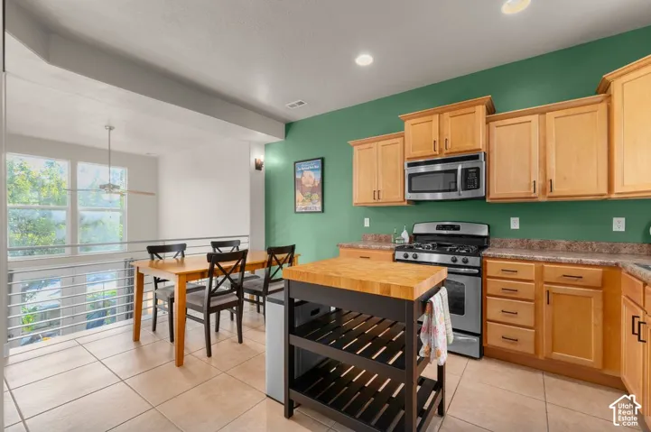 Kitchen area featuring stainless steel appliances, wood-finish cabinetry, and recessed lighting