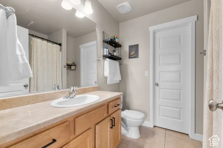 Bathroom featuring a single vanity with an integrated sink, light wood-finish cabinetry, a large wall mirror, and a shower with a curtain