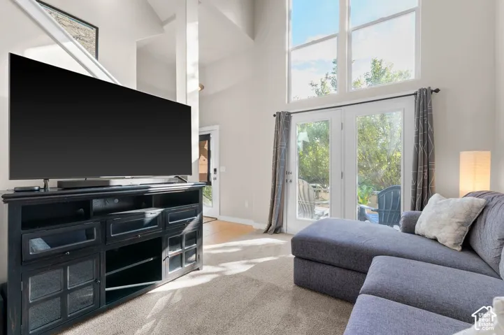 Light-filled living area featuring a vaulted ceiling, transom windows, and double French doors to the exterior