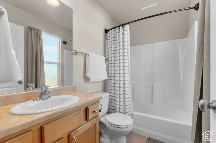 Bathroom featuring a wood-finish vanity with an integrated sink, a large wall-mounted mirror, and a full-size bathtub with a shower