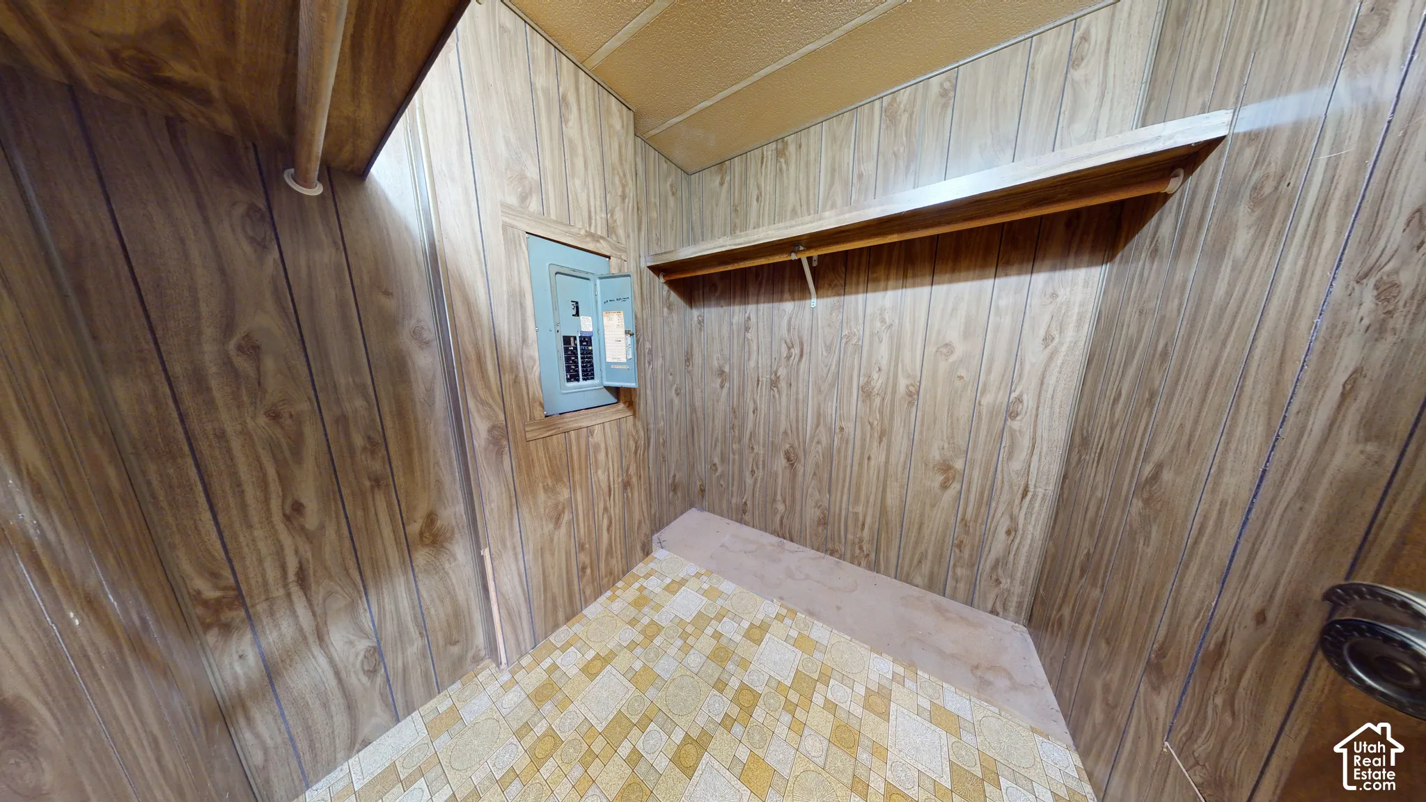 Storage area featuring wood-finish paneling, built-in shelving, and patterned vinyl flooring