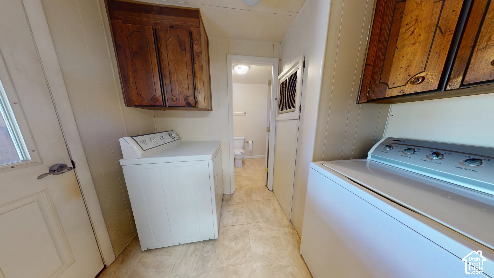 Laundry area featuring wooden cabinetry, white washer and dryer, and tile-finish flooring