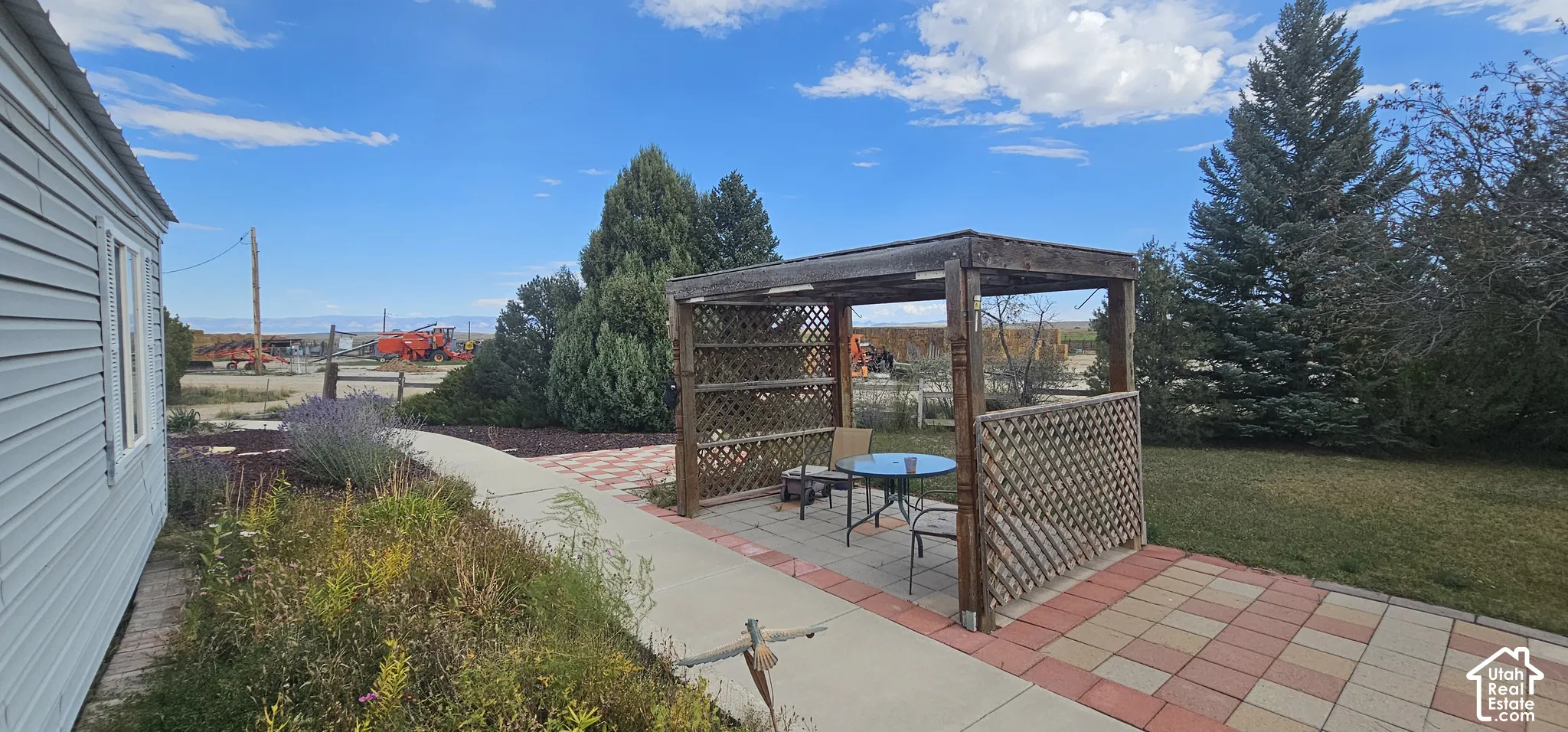 Wood pergola with lattice accents, paver patio, and concrete pathway