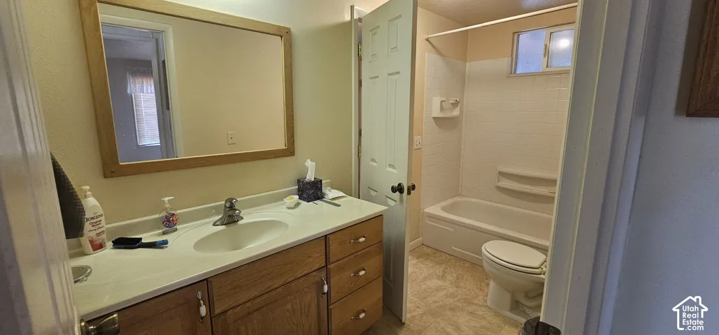 Bathroom featuring a wood-framed mirror, wood-finish vanity with an integrated sink, polished chrome faucet, white tiled shower surround, and a tub/shower combination