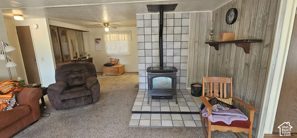 Wood-burning stove with a tile surround, wood-finish wall paneling, and ceiling fan