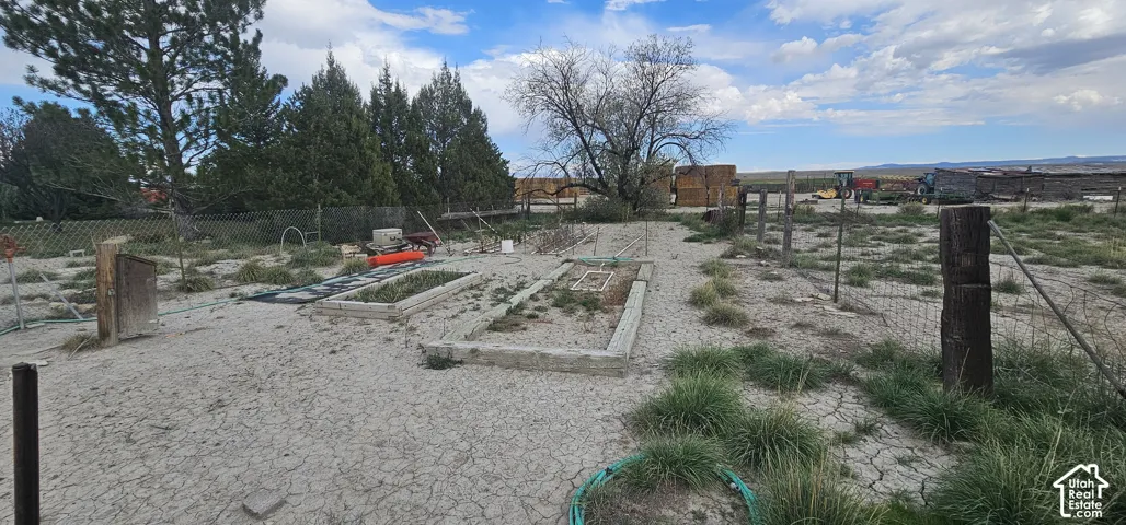 Expansive lot featuring multiple raised garden beds, mature trees, and a perimeter fence