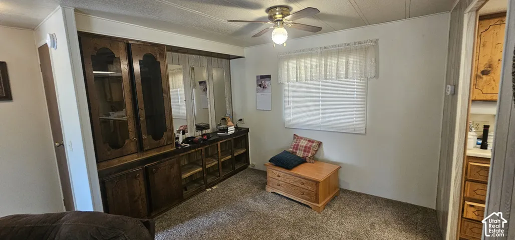 Built-in wood-finish cabinetry with glass-front uppers, ceiling fan with integrated lighting, and window with blinds