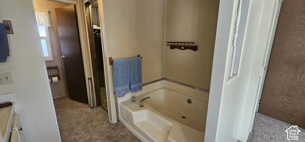White soaking tub with built-in steps, chrome fixtures, and a wood-finish towel bar