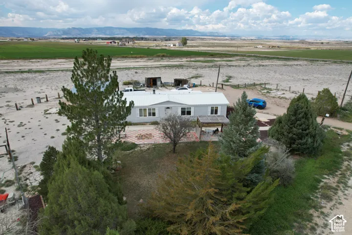 Expansive property featuring a single-story residence, a covered porch, established trees, and surrounding agricultural areas