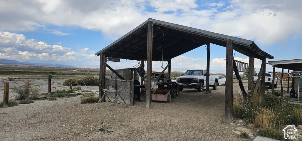 Open-air wooden structure featuring a corrugated metal roof and gravel ground cover