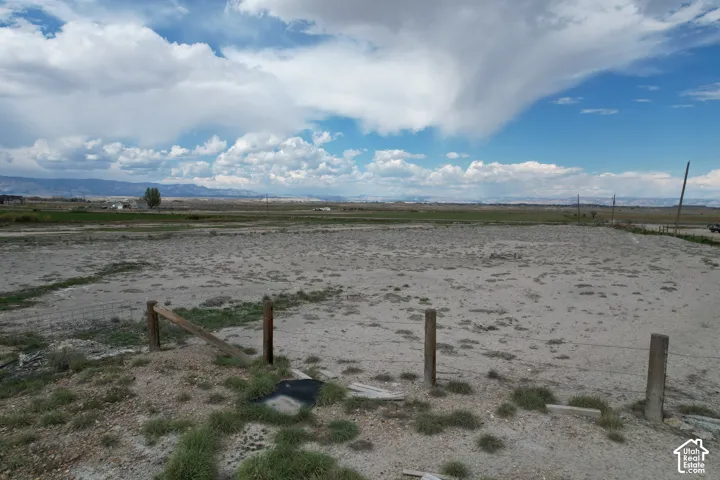 Expansive open land featuring distant mountain ranges and a partially fenced perimeter
