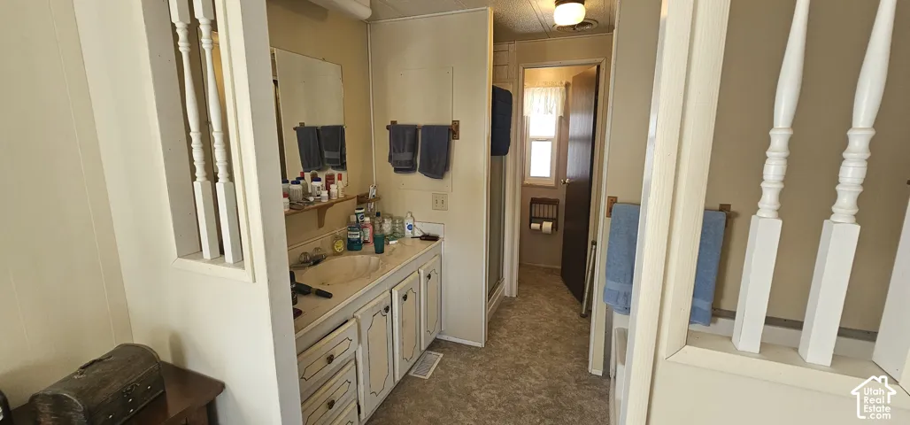 Vanity with integrated sink, wood-finish cabinetry, and overhead lighting