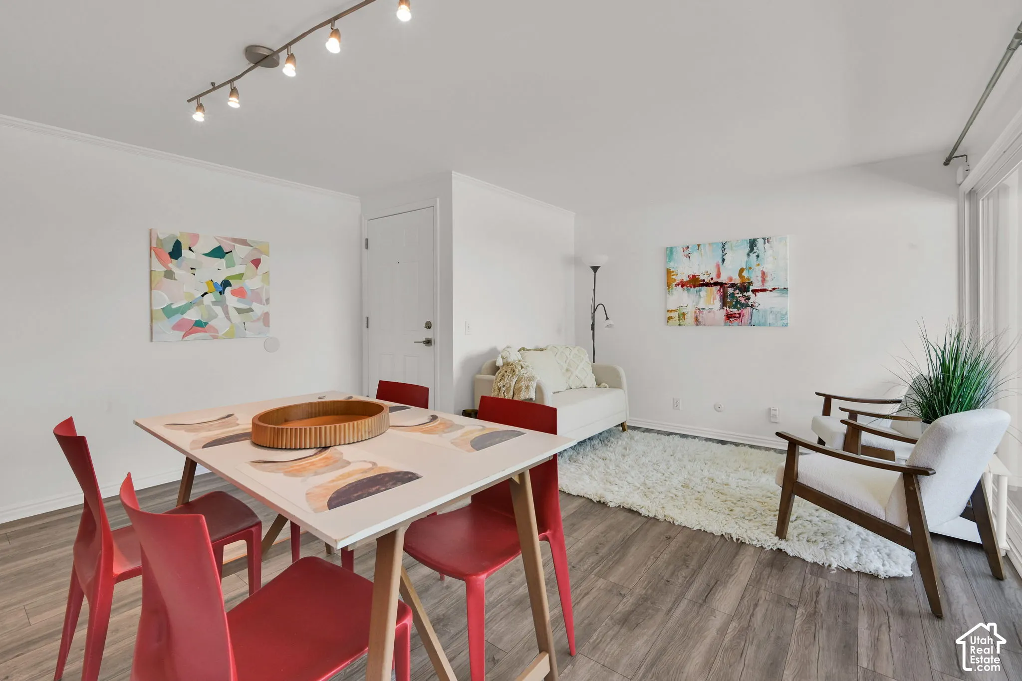 Wood-finish flooring throughout, track lighting fixture, white walls, and a white interior door