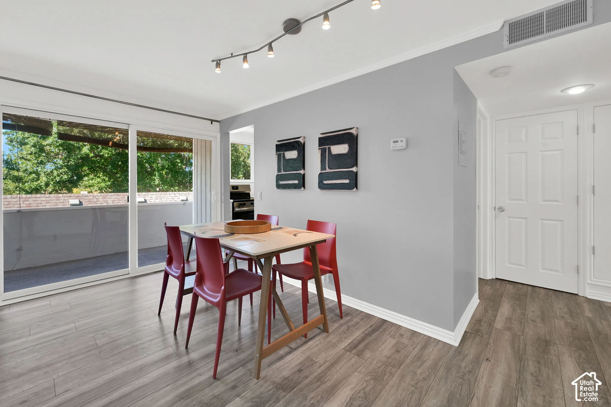 Sliding glass door to balcony, wood-finish flooring, track lighting, and a paneled interior door