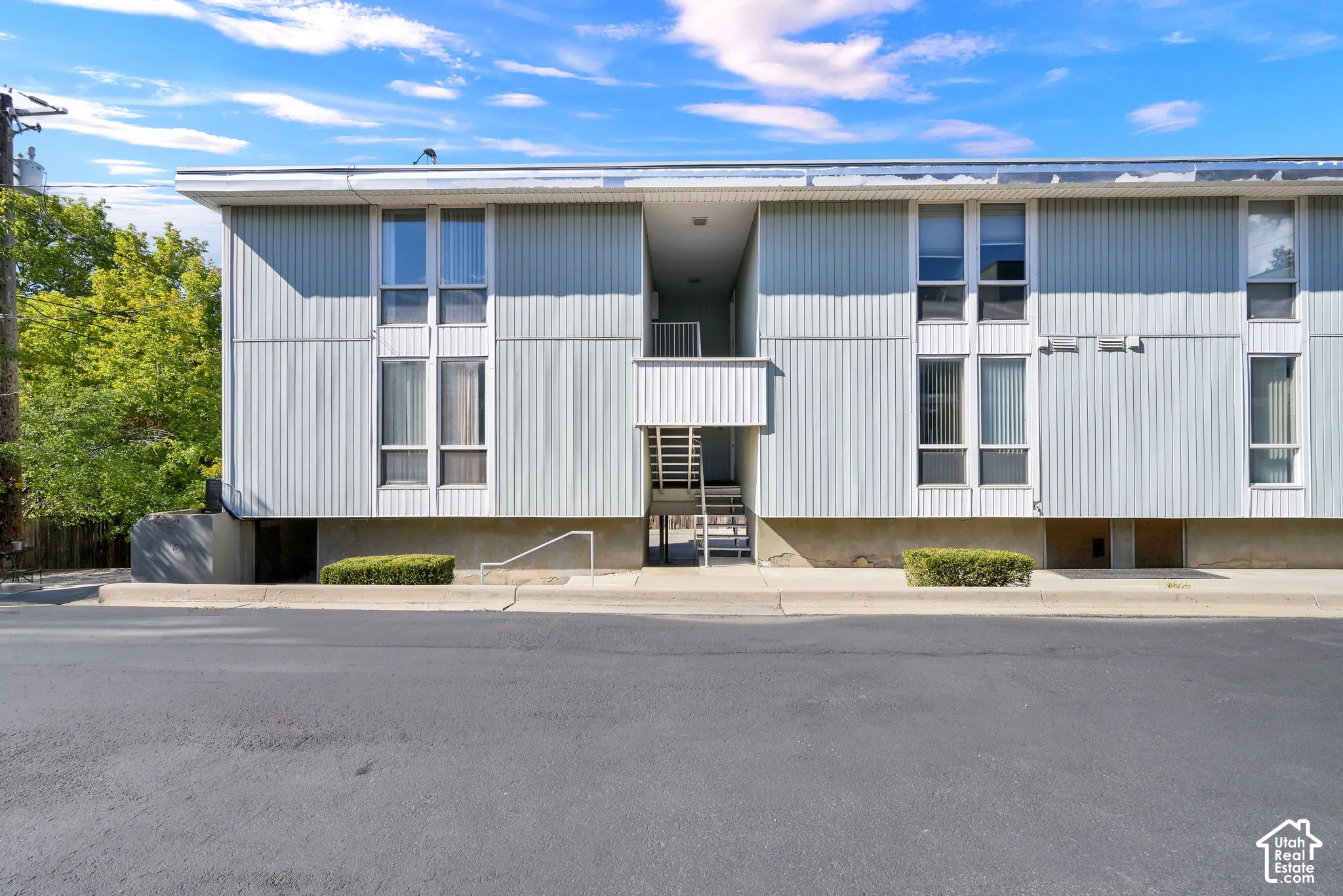 Multi-level structure featuring vertical siding, multiple windows, and a central exterior staircase