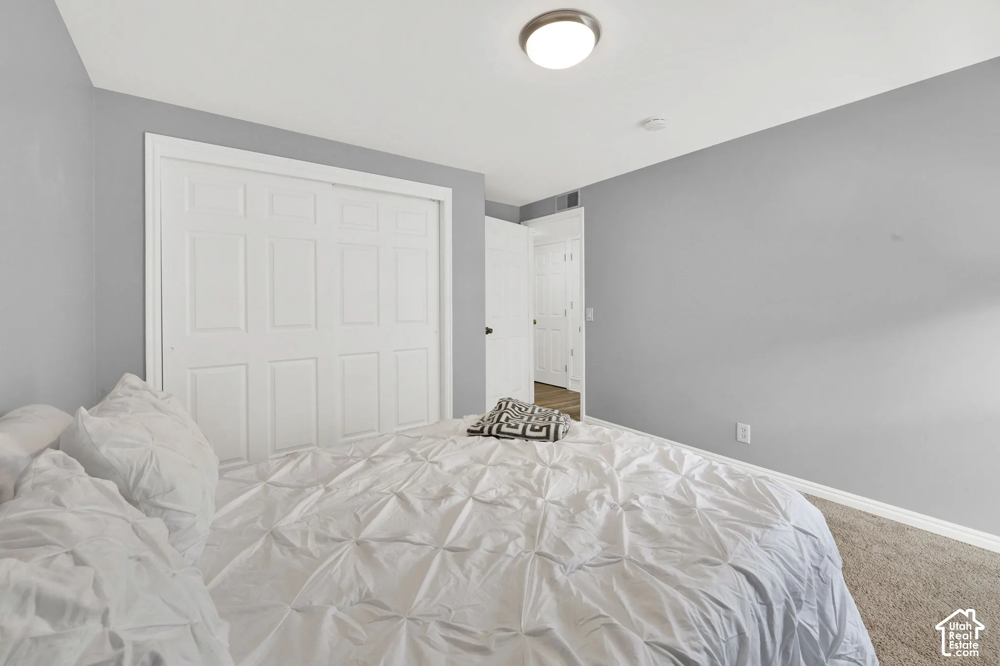 Carpeted room with a ceiling-mounted light fixture, light gray walls, and white trim