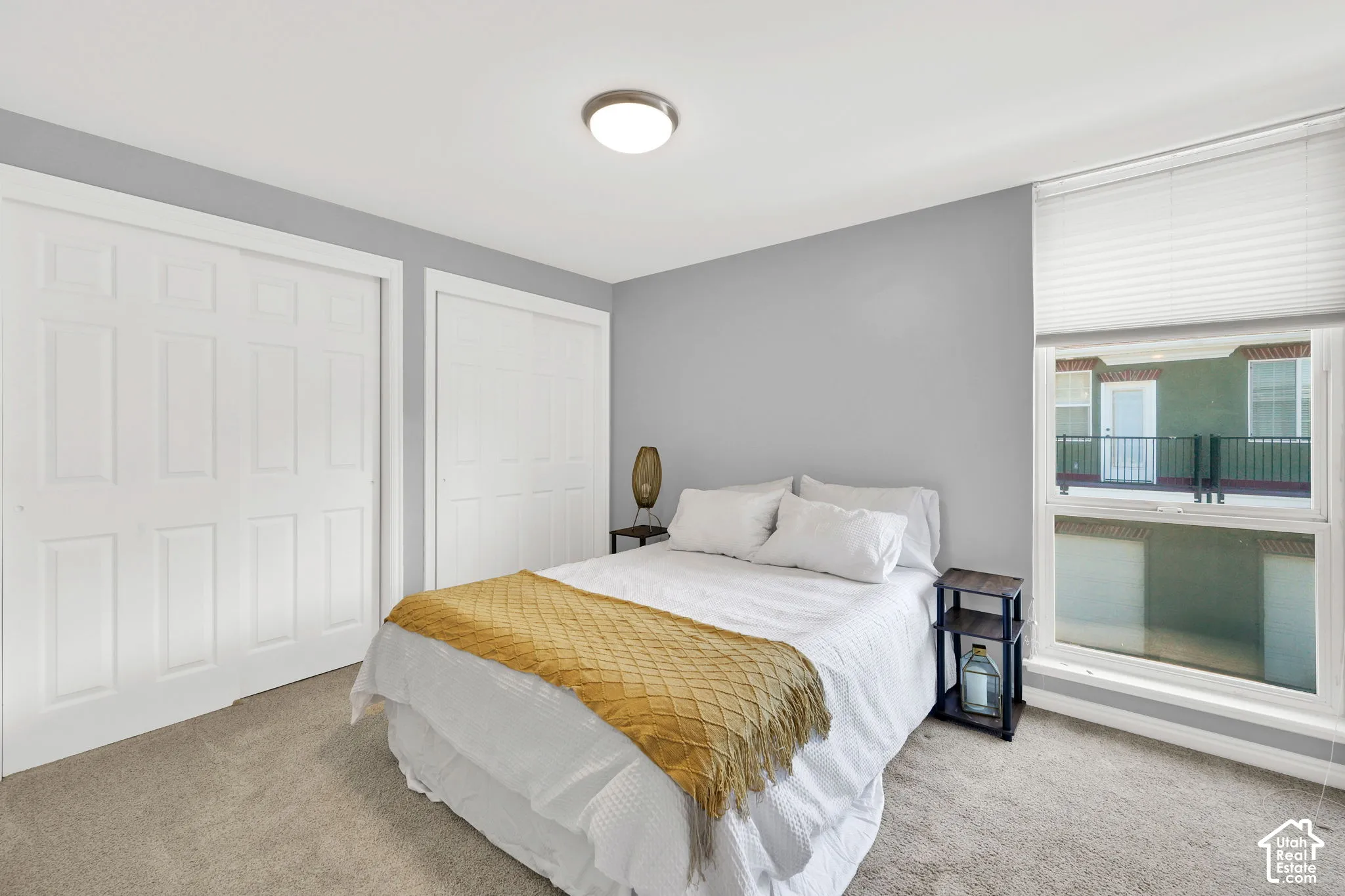White paneled closet doors, neutral wall color, and a window with blinds