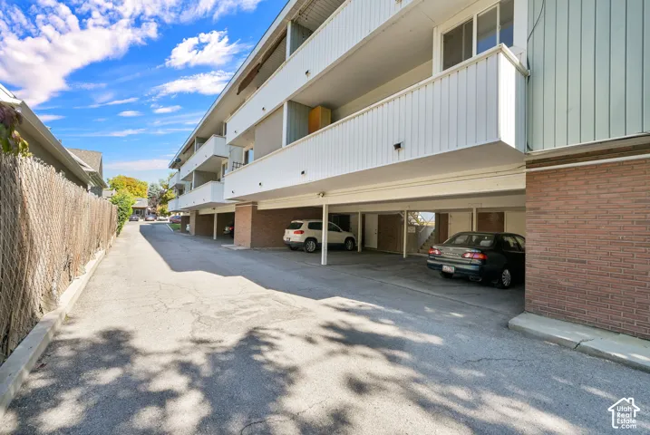 Multi-story apartment building with balconies, brick siding, and an open covered parking area