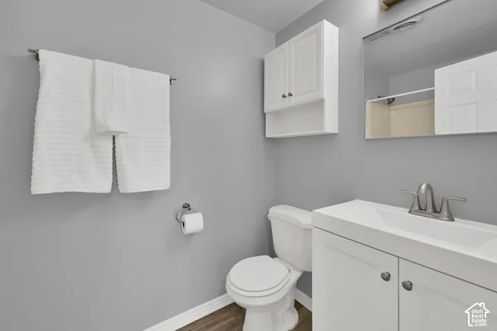 Bathroom featuring a white vanity with integrated sink, brushed nickel faucet, wall-mounted medicine cabinet, and white upper cabinetry