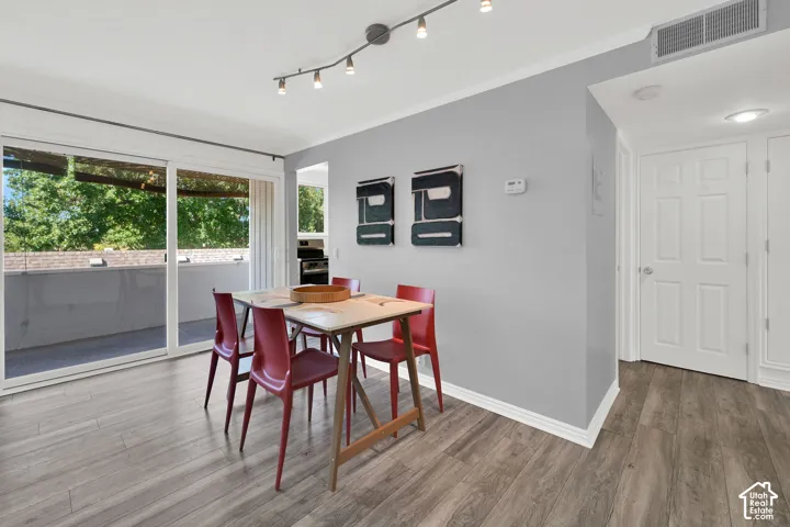 Sliding glass door to balcony, wood-finish flooring, track lighting, and a paneled interior door