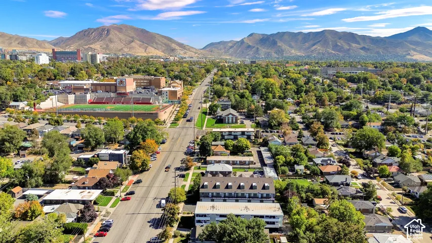 Expansive urban landscape featuring tree-lined streets, residential architecture, and distant mountains