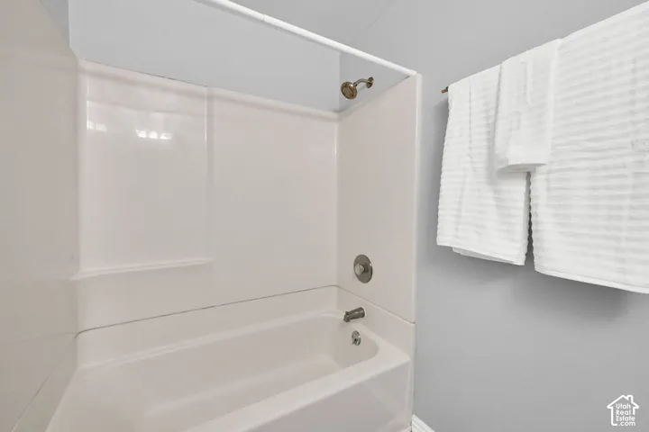 Bathtub with an integrated shower surround, bronze-finish shower head, and brushed nickel fixtures