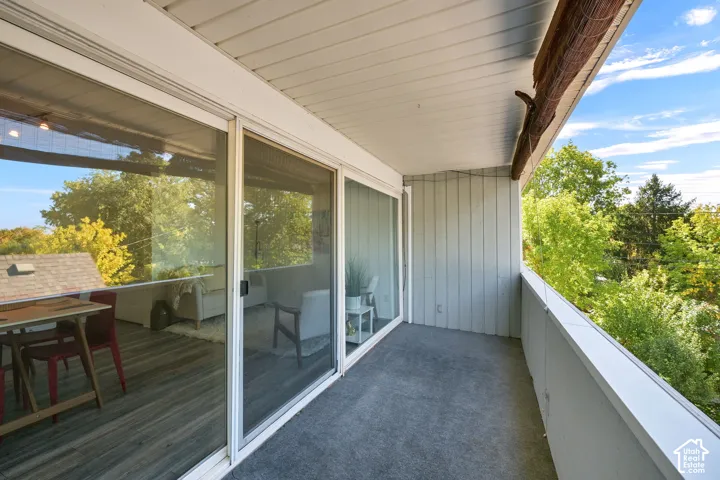 Exterior balcony with gray-toned flooring, white railing, and sliding glass doors