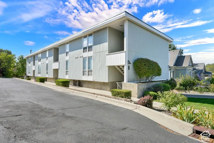 Multi-unit building featuring light-colored siding, multiple windows, and exterior stair access