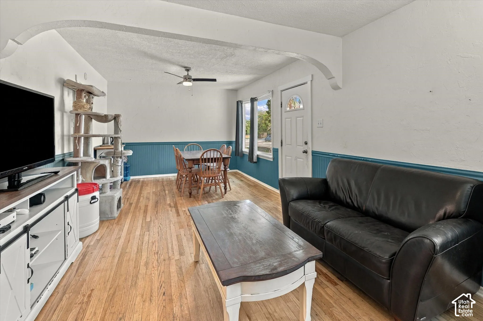 Hardwood flooring, painted wainscoting, and a ceiling fan with integrated lighting
