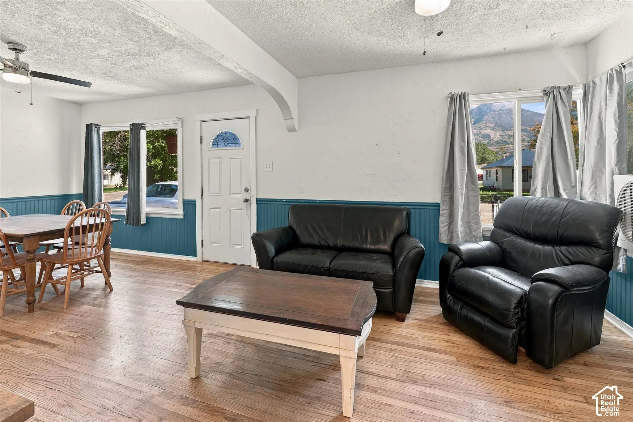 Wood-finish flooring, white walls, and a front entry door with an arched glass insert