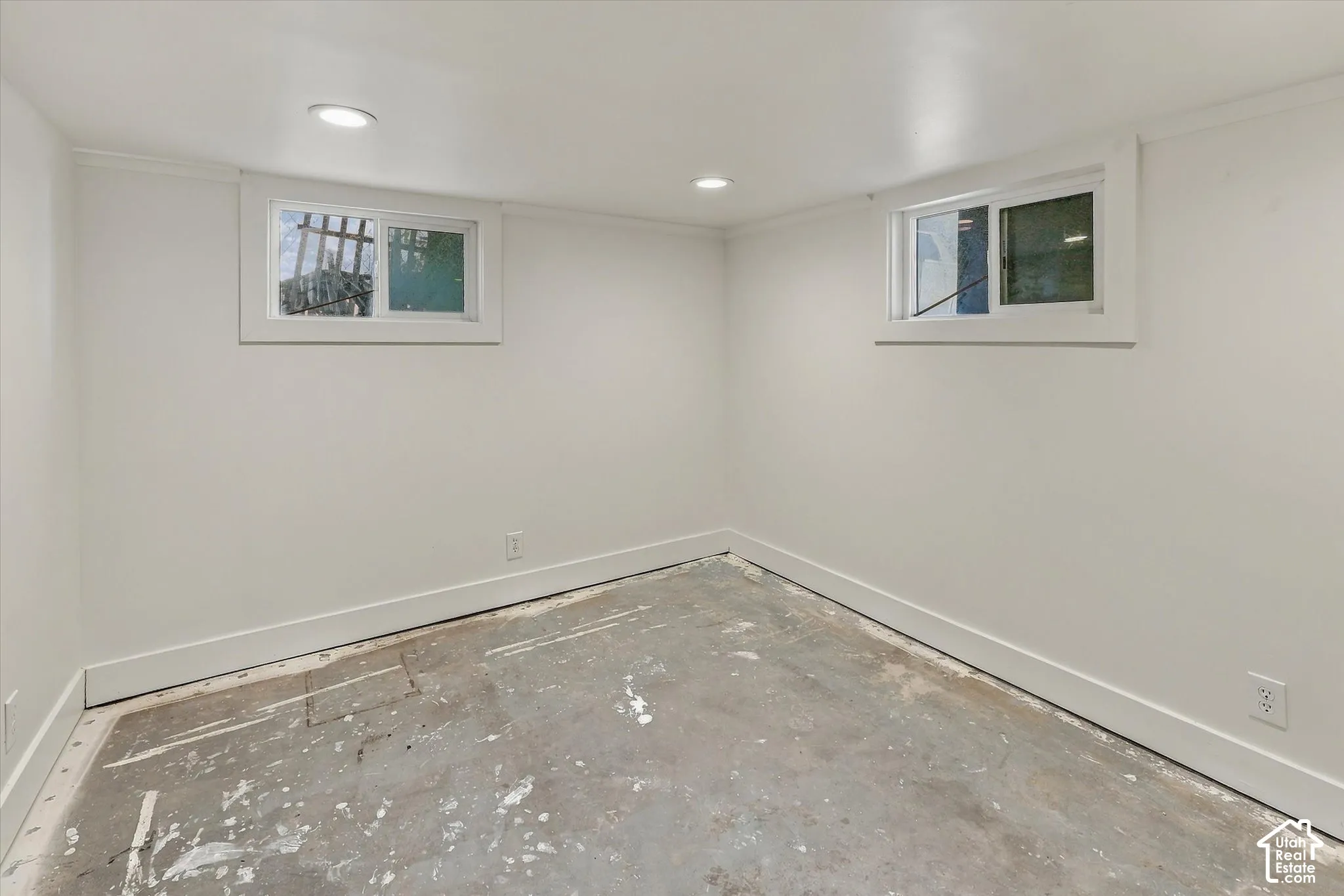 White painted walls, recessed lighting, white window trim, and a concrete subfloor