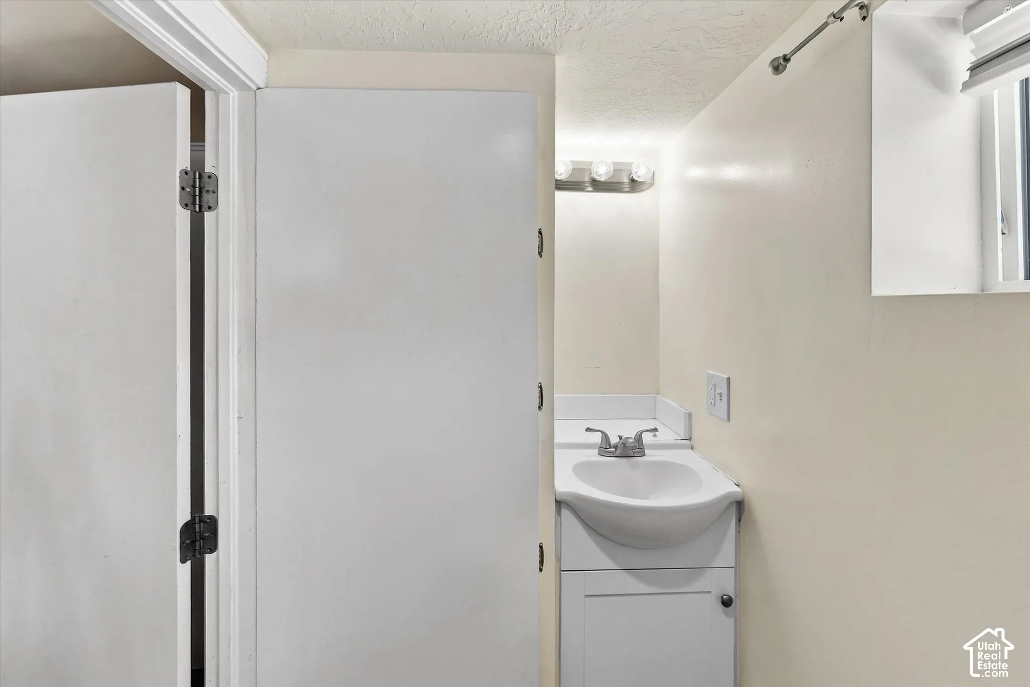 White vanity with integrated sink, chrome faucet, and overhead bar lighting fixture