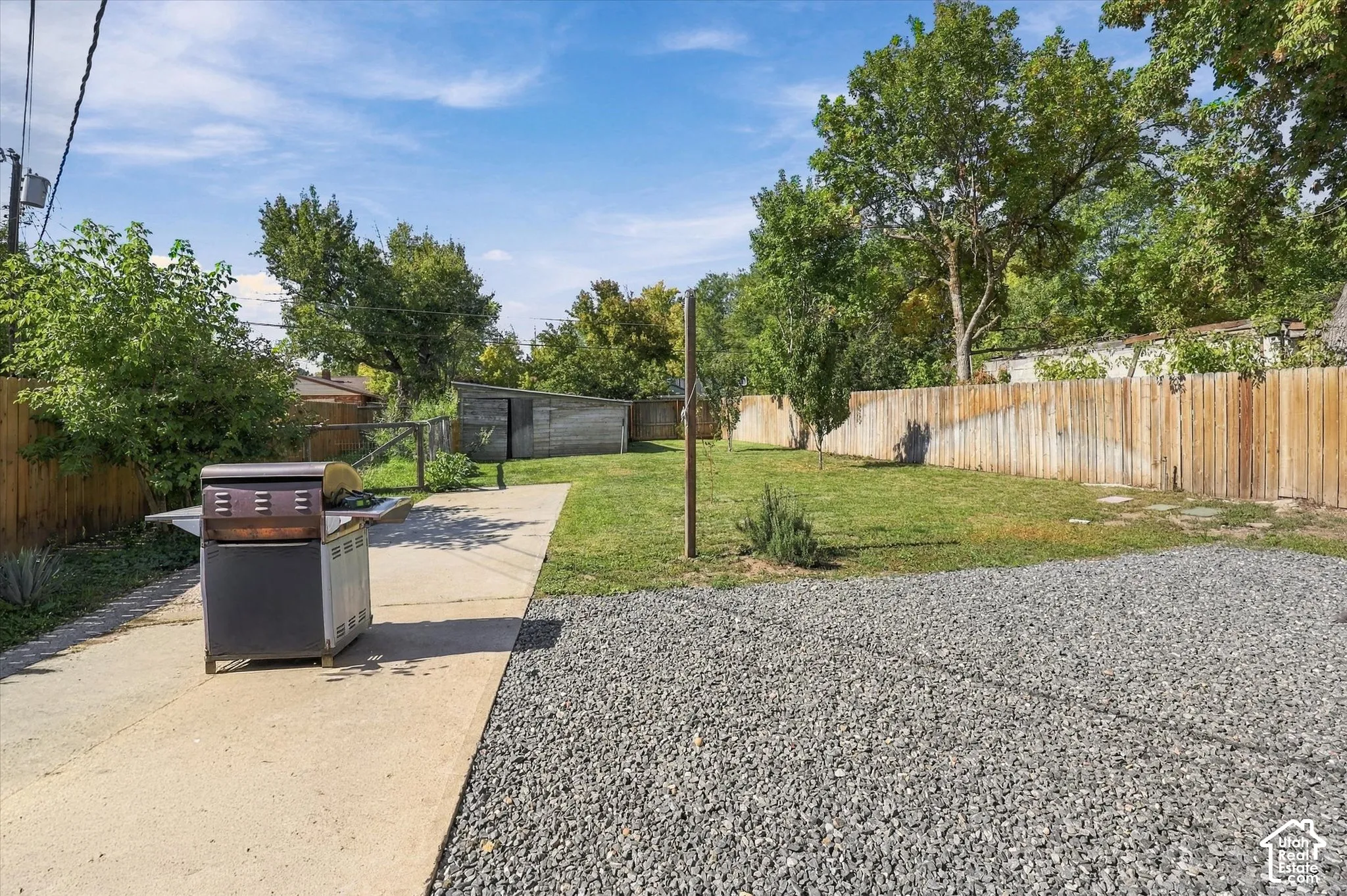 Expansive rear yard featuring a gravel area, concrete pathway, and a grass lawn